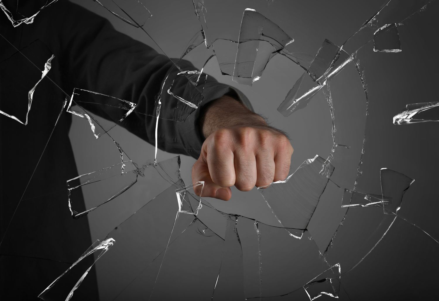 Man breaking window with fist on grey background, closeup.