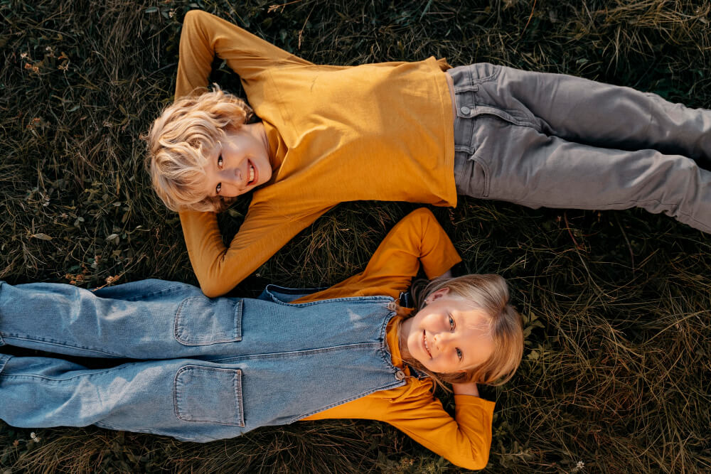 Medium shot kids laying gras.