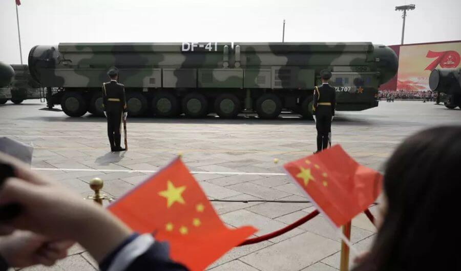 Spectators wave Chinese flags as military vehicles carrying DF-41 nuclear ballistic missiles roll.